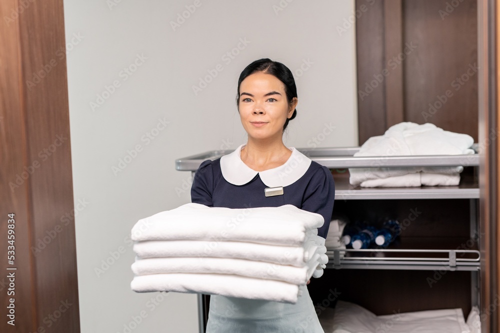 Poster Ai generated face of pretty room service staff holding clean sheets while standing by open door
