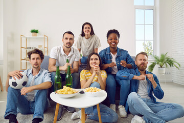 Group of happy diverse multiracial friends watching football on TV at home. Young mixed race people sitting on sofa, watching sports match, waiting for goal and hoping for victory all together - Powered by Adobe