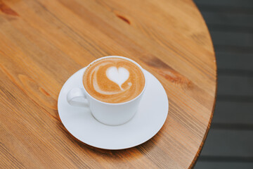 Delicious cappuccino with a beautiful foam on a wooden table with a place for text. Freshly brewed...