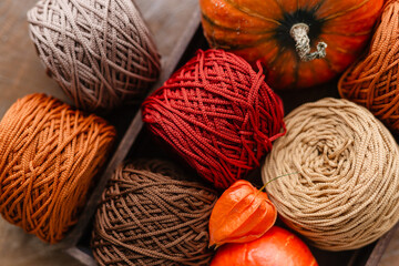 Knitted yarn coils for knitting in a wooden box with pumpkins. Atmospheric autumn shades of thread...