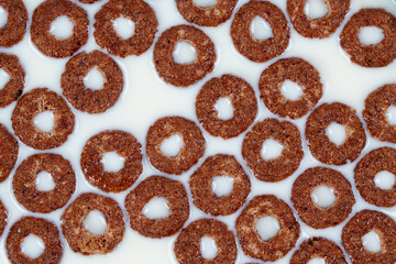 Cold chocolate rings, quick breakfast for kids. Sweet cereals. Brown wooden background