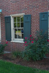 Street reflection in window with green shutters set in brick building