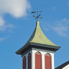 Fototapeta na wymiar Cupola with copper cap wind vane against blue skies