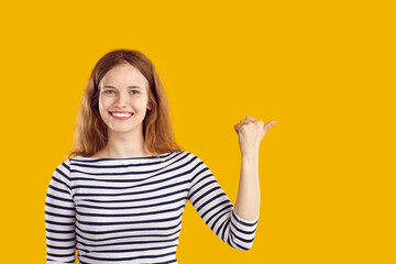 Pretty woman showing something isolated on solid yellow copy space background. Studio portrait of...