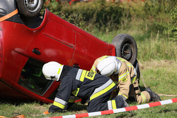 Akcja straży pożarnej podczas wypadku samochodowego. Ratowanie rannego kierowcy.. Ćwiczenia straży pożarnej.  - obrazy, fototapety, plakaty