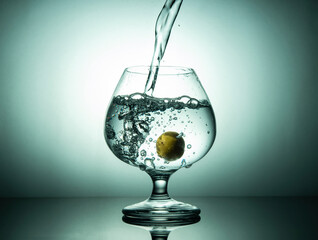 Fresh drinking water pouring into glass with lemon, healthy lifestyle concept