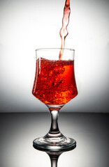 Red color juice pouring into glass with clean background