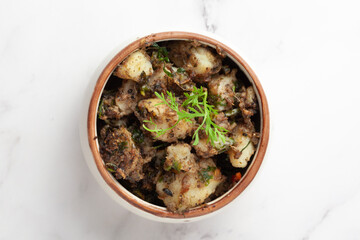 Macro Close-up of Indian vegetarian classic dish Jeera Aloo - Potatoes Flavored with Cumin  garnished with green coriander fresh leaves and green chilli.