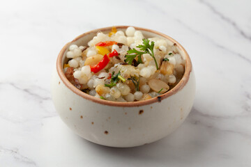 Close-up of Sabudana Khichadi - An authentic dish from Maharashtra made with sago seeds and garnished with coriander leaves served in ceramic bowl