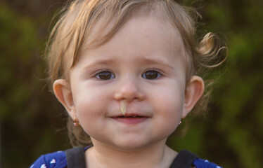 Baby plays snot in the street with a cold nose. Selective focus. - obrazy, fototapety, plakaty