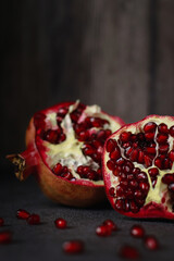 close up of a cut pomegranate on grey table and wooden dark background