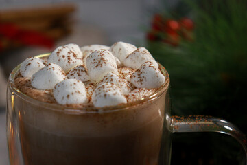 close up of mini marshmallows on hot chocolate in a glass mug, blurred lights background 