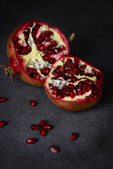 close up of a cut pomegranate on grey table and wooden dark background