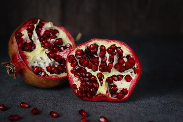 close up of a cut pomegranate on grey table and wooden dark background