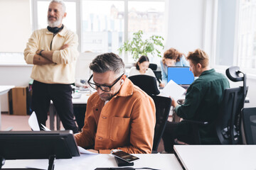 Man reading documents in office with colleagues