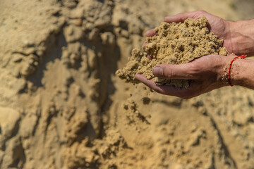 Sand in the hands of a man. Selective focus.