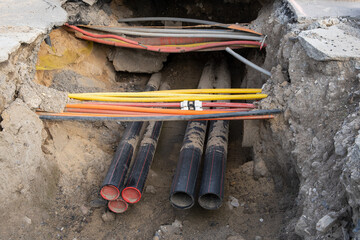 Network cables in red corrugated pipe are buried underground on the street. underground electric...