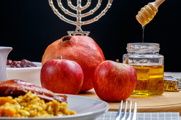 challah, wine, apples and honey dripping honey from a spoon into a jar.