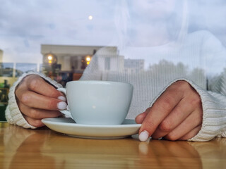 Women's hands hold a warm cup of coffee in winter. Home comfort.