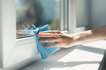 hand with cleaning cloth wipe window frame in apartment - obrazy, fototapety, plakaty