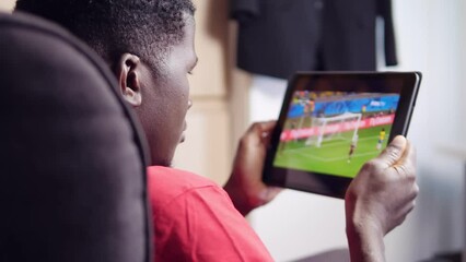 Man watching a soccer tv game on digital tablet - Powered by Adobe
