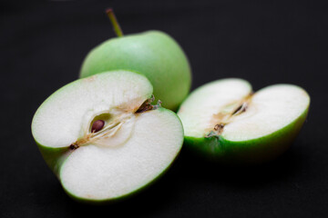 Green apple on a dark background. A cut green apple on a black background. Healthy food