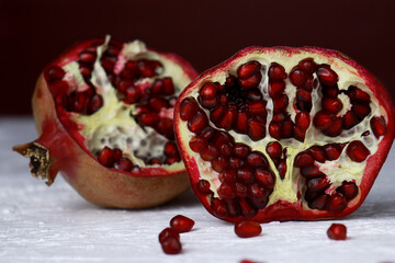 close up of a cut pomegranate on white table, red background with copy space