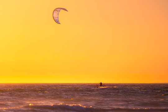 Kite surfer above rippling water in sunset