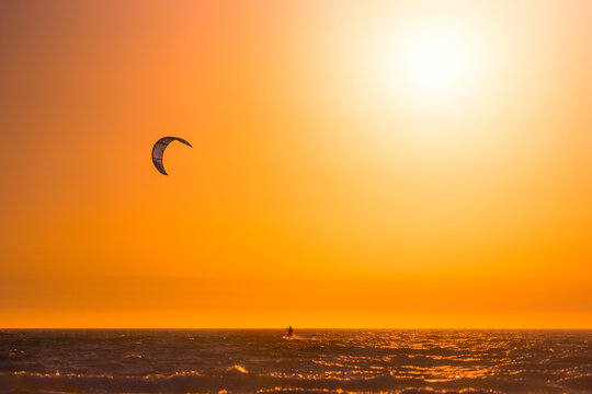 Kitesurfer above rippling water in sunset