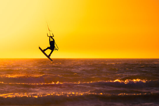 Kite surfer above rippling water in sunset