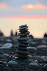 Stones pyramid on sand symbolizing zen, harmony, balance. Black sea at sunset in the background.