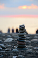 Stones pyramid on sand symbolizing zen, harmony, balance. Black sea at sunset in the background.