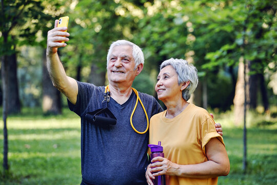 Old sportive couple using smartphone outdoors
