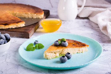 Appetizing thin cheesecake with honey and blueberries on a plate on the table. Homemade pastries