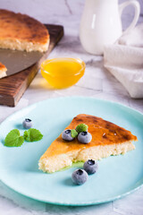 A piece of cheesecake with honey and blueberries on a plate. Homemade pastries. Vertical  view