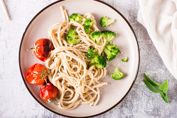Wheat udon noodles in soy sauce with tomatoes and broccoli on a plate. Top view. Closeup
