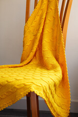 ケーブル編みの編み模様で編んだ黄いひざ掛け