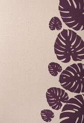 Tropical Monstera Leaves on a Light Beige Background. Simple Modern Composition with Burdundy Paper Cut Palm Tree Leaves ideal for Card, Greetings.Top-Down View. No text. © Magdalena