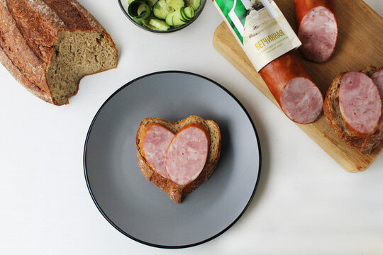 sandwich with sausage on a gray plate in the shape of a heart. Valentine's Day Food Themed