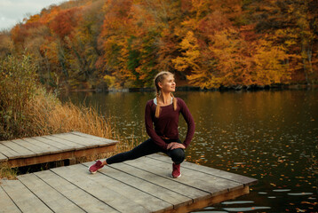 A young beautiful woman is doing sports in the autumn forest