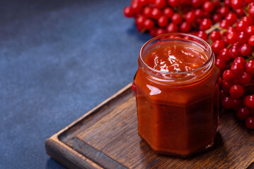 Viburnum fruit jam in a glass jar on a dark concrete background
