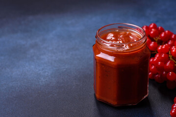 Viburnum fruit jam in a glass jar on a dark concrete background