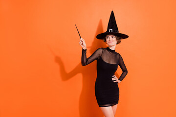 Photo of lovely young lady wave magic stick wear stylish halloween witch black hermione granger costume isolated on orange background - obrazy, fototapety, plakaty