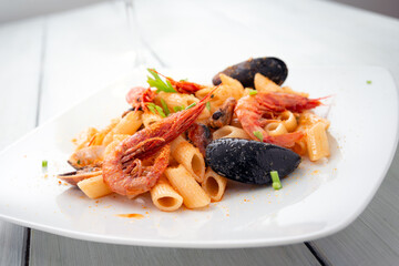 Piatto di deliziose penne rigate condite con frutti di mare e bottarga di muggine, cibo italiano 