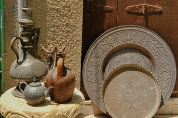 Arabian-style cookware in the street souvenir store.Traditional Gulf and African countries utensil, ancient brass trays and silver kettle, jug with oriental pattern on display of middle eastern souk.