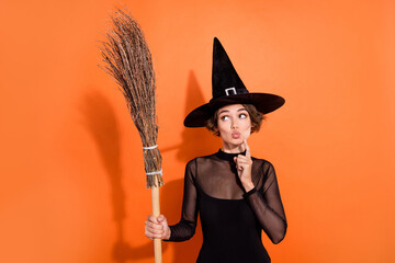 Portrait of charming witch person finger touch chin pouted lips look empty space hold broom...