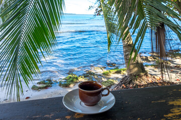 Taza de café y playa en el caribe 
