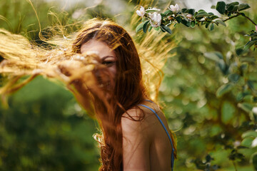 Portrait of a woman with long flyaway hair red hair in summer, the concept of health and care for...