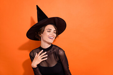Photo of charming funny girl dressed black gothic dress headwear laughing closed eyes empty space isolated orange color background