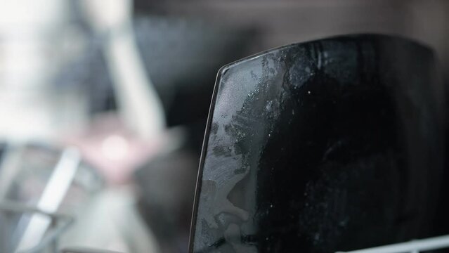 Male hand puts dirty dishes into dishwasher. Black glass plates glisten with dirt and grease against blurred background. Man does cleaning around flat